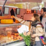 Junges Pärchen am Käsestand eines Wochenmarktes