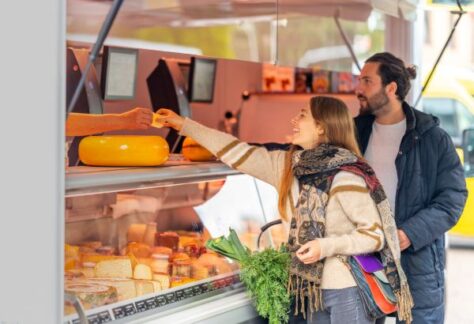 Junges Pärchen am Käsestand eines Wochenmarktes