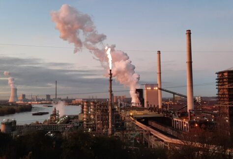 Blick auf den Rhein und die Kokerei Schwelgern mit Wasserdampf und Werksbeleuchtung.